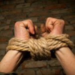 Hands of man tied up with rope